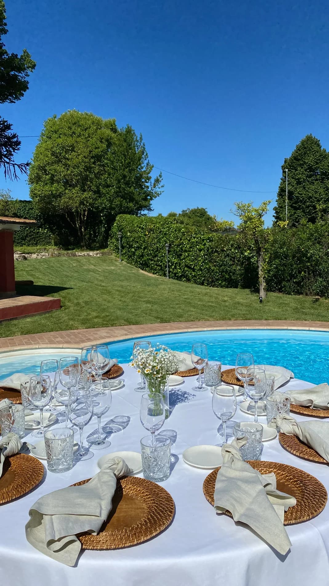 Tavolo elegante allestito a bordo piscina, con cristalli e centrotavola di campo