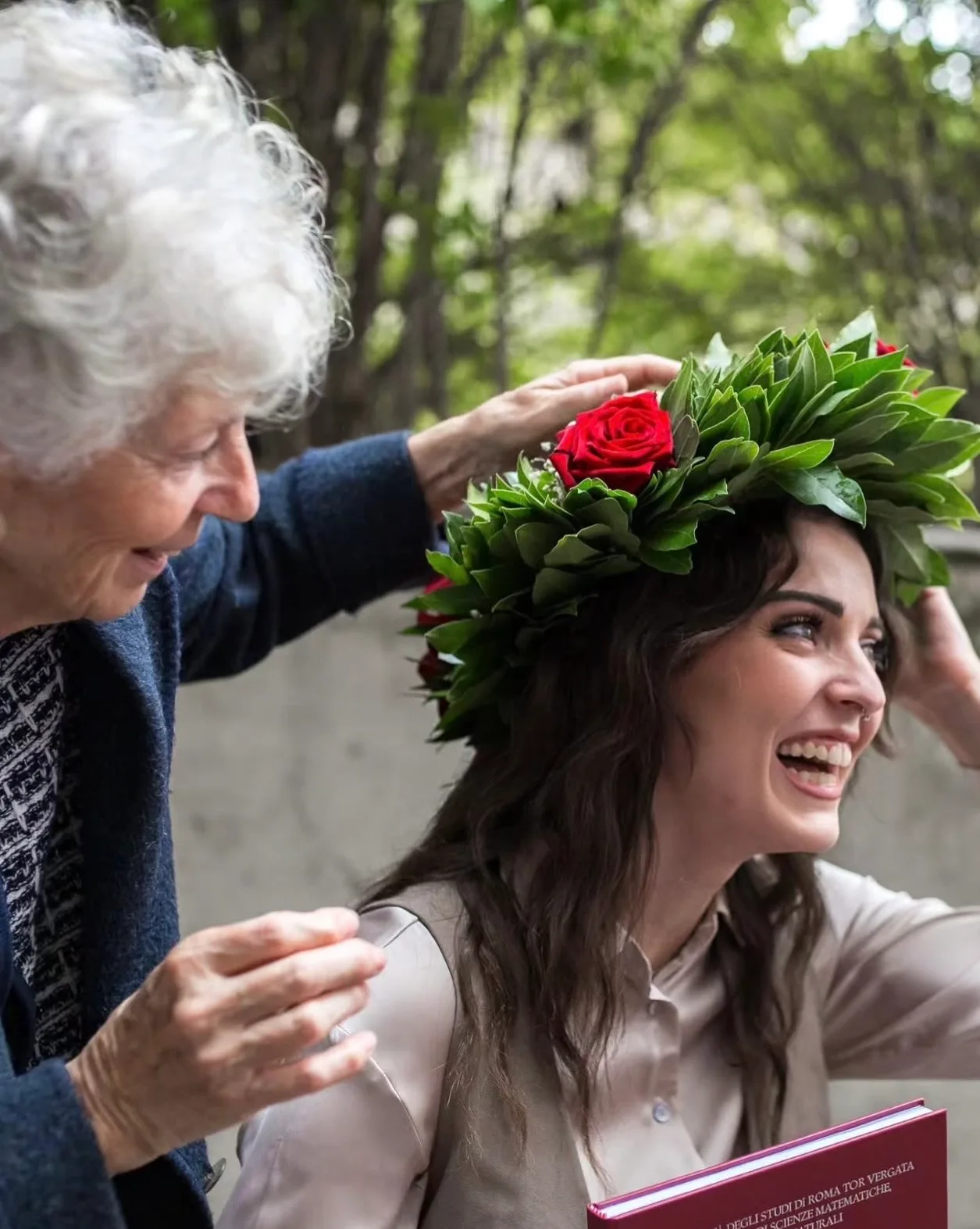 Una nonna posa la corona d'alloro sul capo della nipote neolaureata, sorridendo