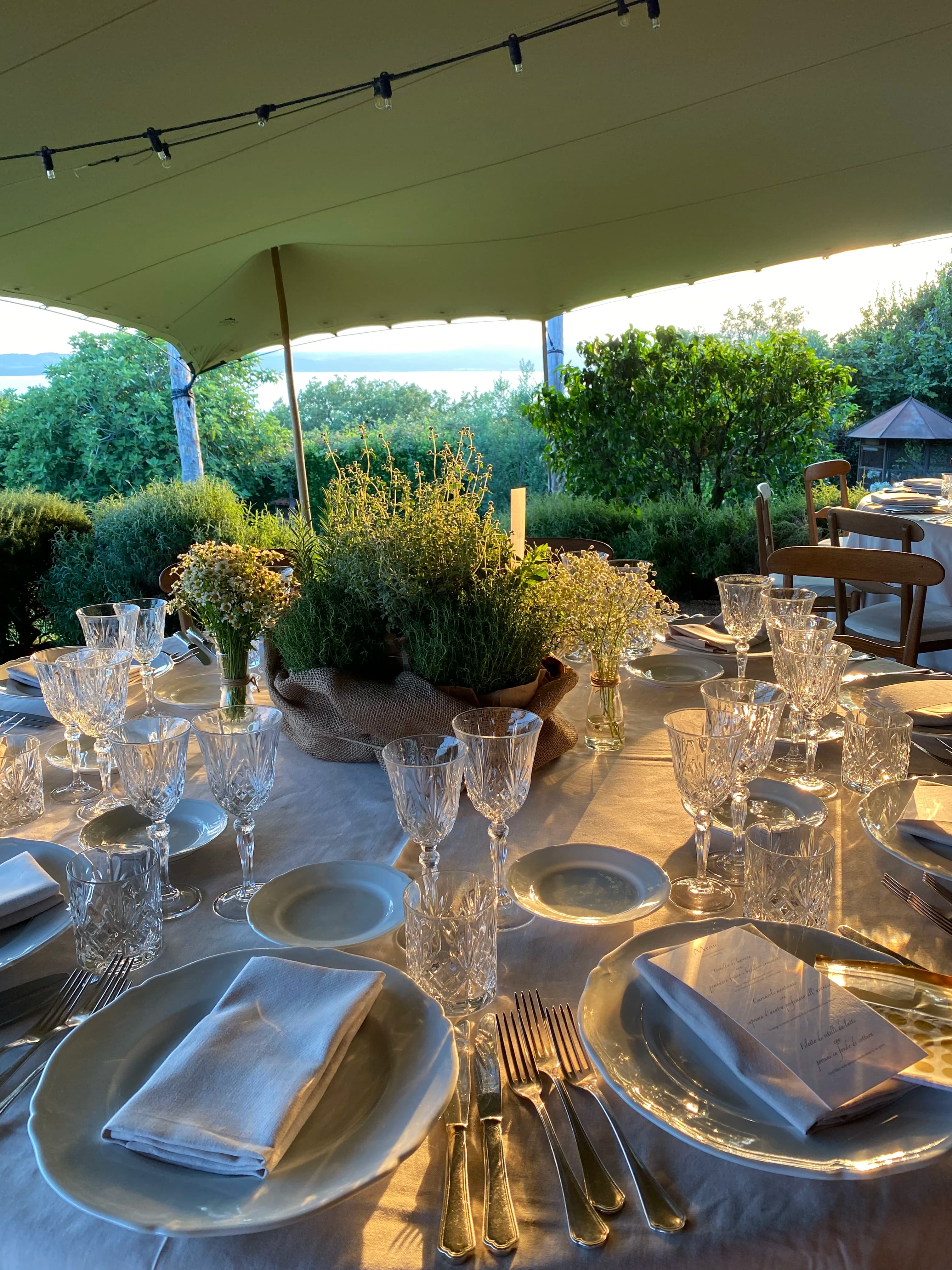 Tavolo del ricevimento allestito sotto il gazebo al tramonto con vista lago e cristalli